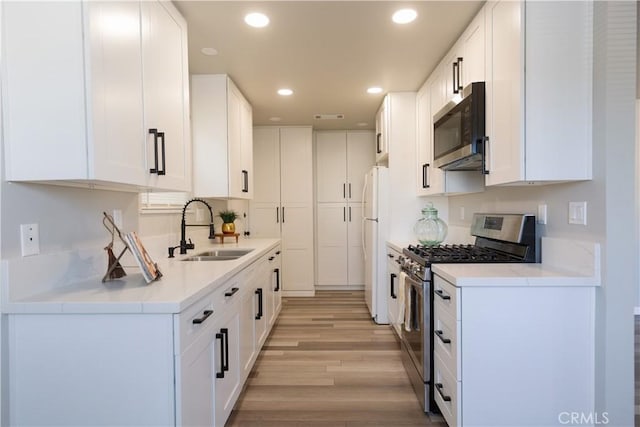 kitchen featuring a sink, appliances with stainless steel finishes, white cabinets, and recessed lighting