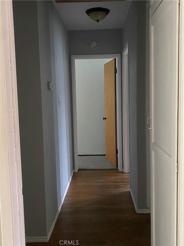 corridor featuring baseboards and wood finished floors