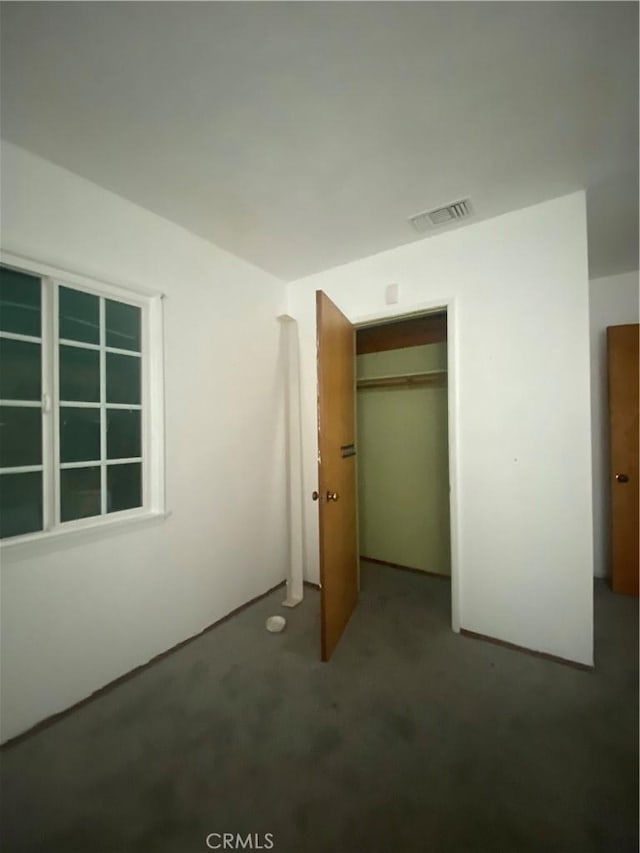 unfurnished bedroom with carpet flooring, visible vents, and a closet