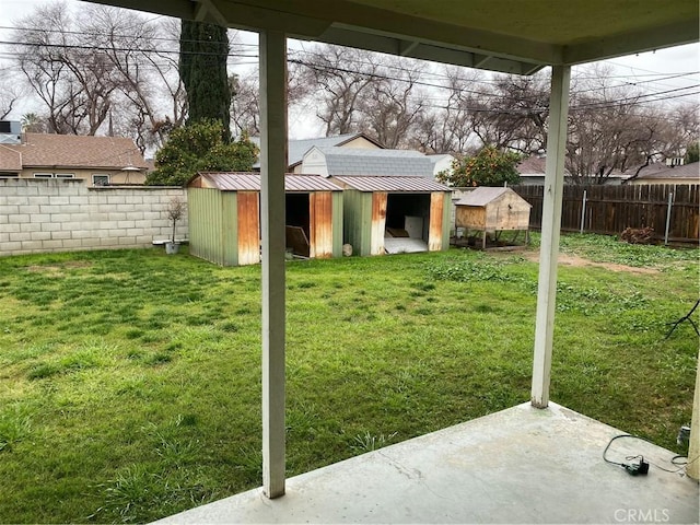 view of yard featuring an outdoor structure, a storage unit, and a fenced backyard