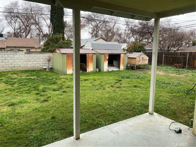 view of yard with a fenced backyard, an outbuilding, and a storage shed