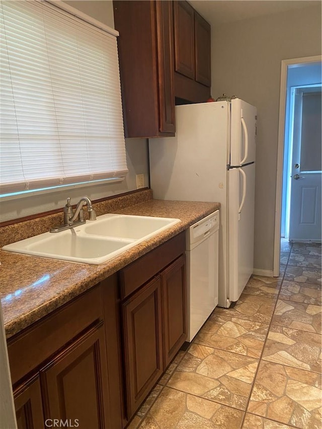 kitchen with a sink, stone finish flooring, and white dishwasher