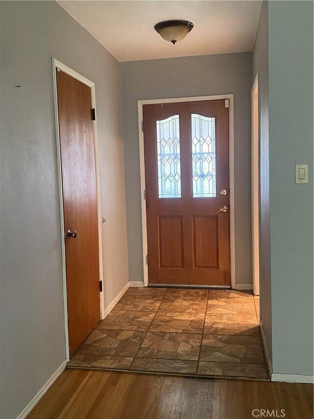 doorway featuring baseboards and wood finished floors