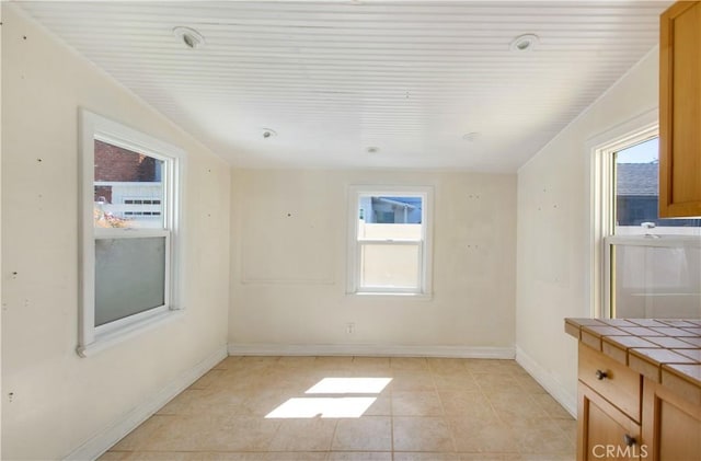 empty room featuring washer / clothes dryer, plenty of natural light, baseboards, and light tile patterned floors