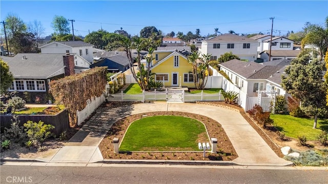 view of front of home featuring a gate, concrete driveway, a front lawn, a fenced front yard, and a residential view