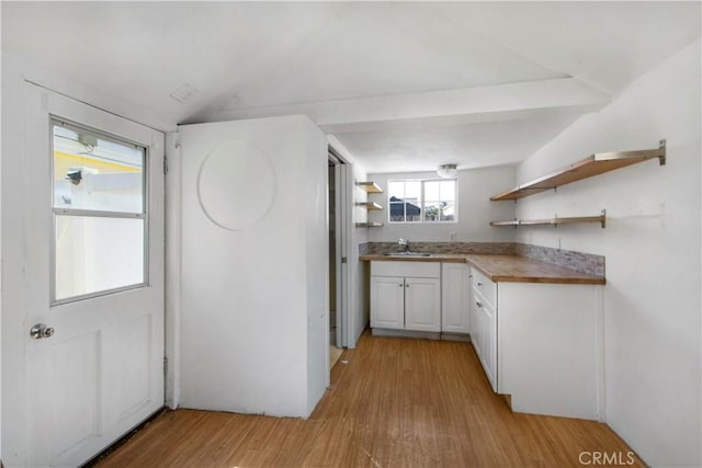 kitchen featuring open shelves, a sink, light wood-style floors, white cabinets, and vaulted ceiling