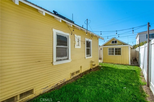 view of side of property featuring a lawn, fence private yard, and an outdoor structure