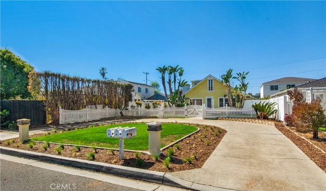 view of front of house featuring fence private yard, concrete driveway, and a front yard