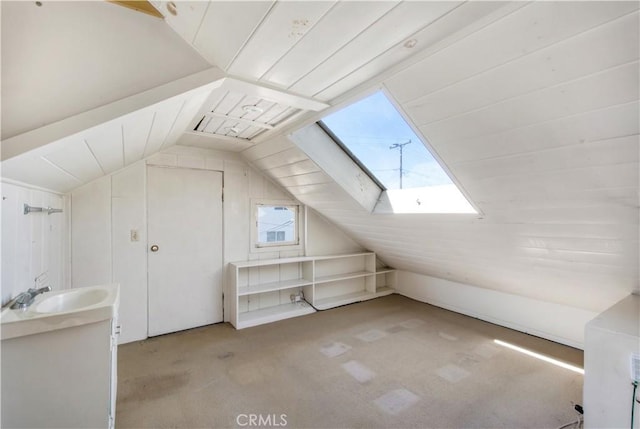 additional living space with a sink, vaulted ceiling with skylight, and carpet