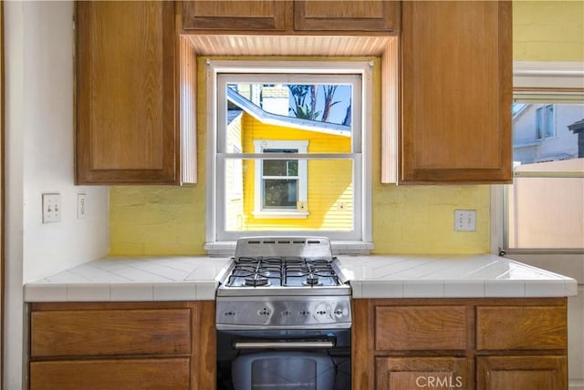 kitchen with range with gas cooktop, light countertops, and brown cabinetry