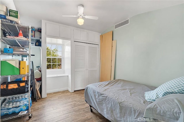 bedroom featuring visible vents, lofted ceiling, wood finished floors, a closet, and a ceiling fan