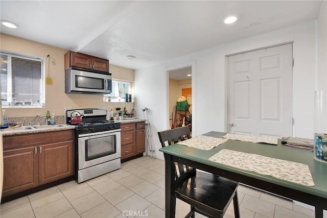 kitchen with a sink, recessed lighting, stainless steel appliances, light tile patterned flooring, and light countertops