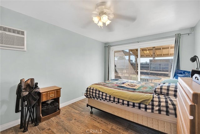 bedroom featuring ceiling fan, a wall mounted air conditioner, baseboards, and wood finished floors