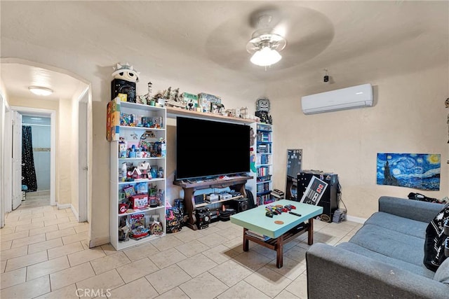 living room with a wall mounted air conditioner, arched walkways, a ceiling fan, and light tile patterned floors