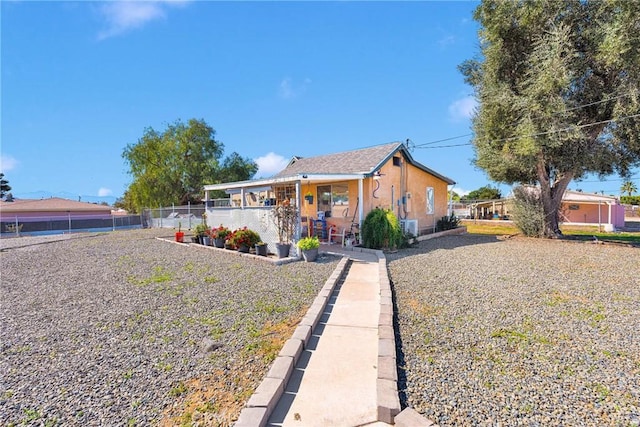 view of front of home with stucco siding, a porch, and fence