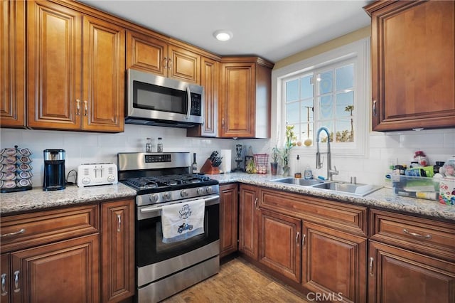 kitchen featuring a sink, decorative backsplash, brown cabinetry, and stainless steel appliances