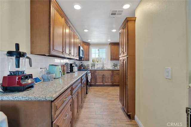 kitchen featuring brown cabinetry, visible vents, appliances with stainless steel finishes, and a sink