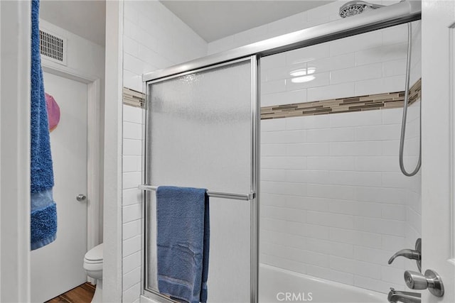 bathroom with visible vents, combined bath / shower with glass door, and toilet