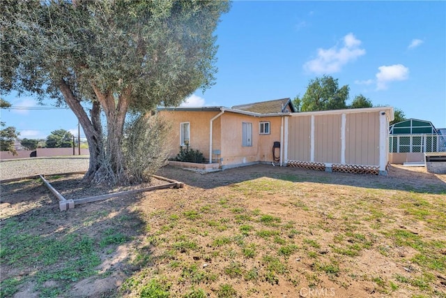 rear view of house featuring a yard and stucco siding