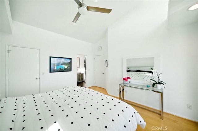 bedroom with connected bathroom, a ceiling fan, light wood finished floors, and high vaulted ceiling