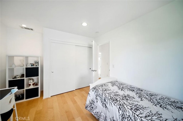 bedroom with recessed lighting, light wood-style floors, visible vents, and a closet