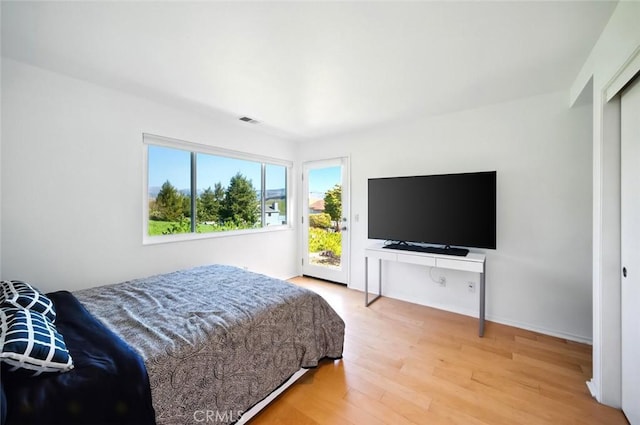 bedroom featuring visible vents, baseboards, wood finished floors, and access to outside