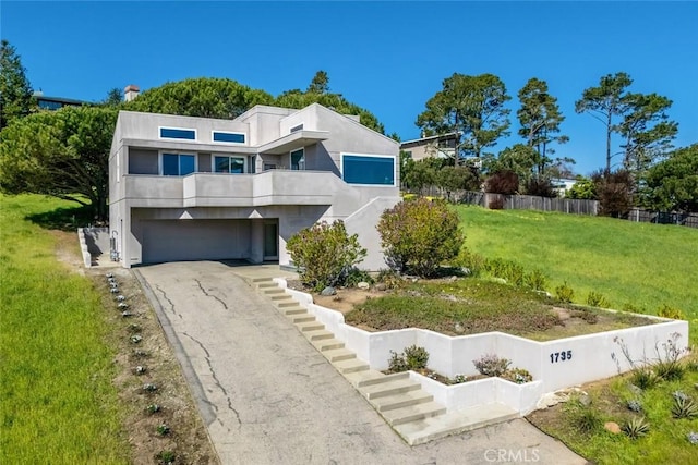 contemporary house featuring stucco siding, a front lawn, driveway, fence, and a garage