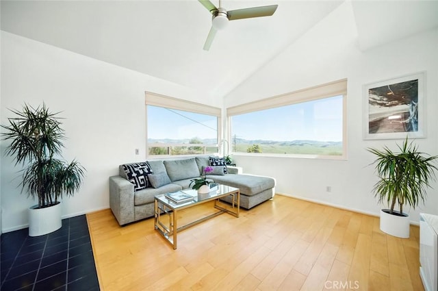 living room with baseboards, light wood-style flooring, a ceiling fan, and vaulted ceiling