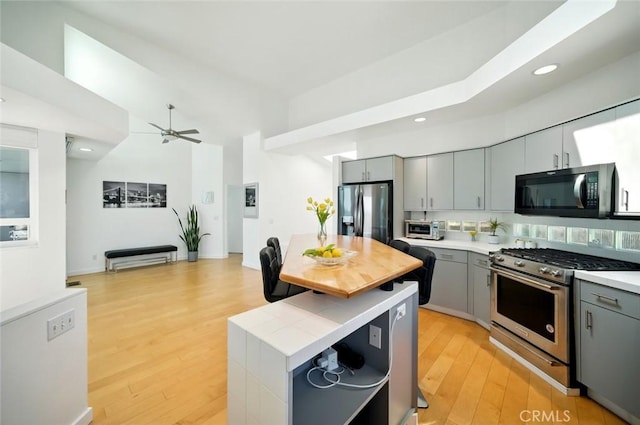 kitchen with light wood-type flooring, stainless steel appliances, and gray cabinetry