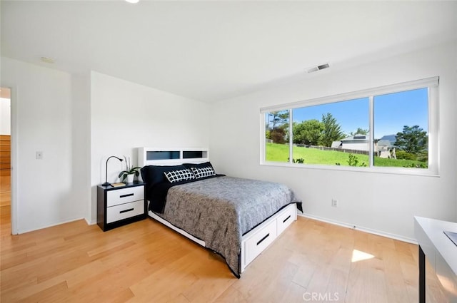 bedroom featuring baseboards, visible vents, and light wood finished floors