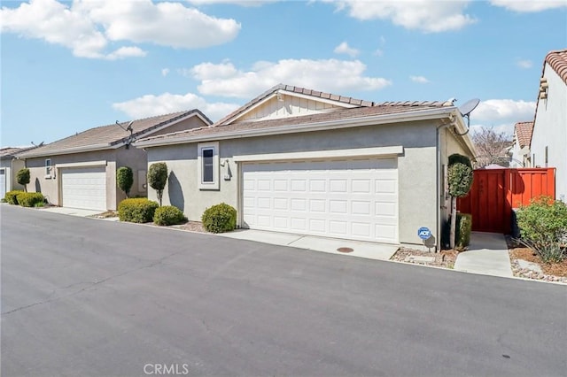 ranch-style home with stucco siding, a garage, and fence