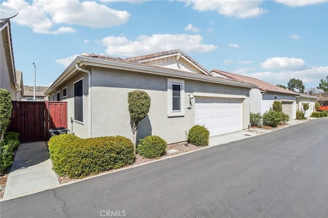 view of side of home featuring a garage, driveway, and stucco siding