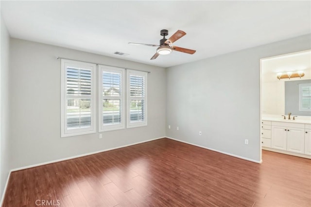 unfurnished bedroom with a sink, visible vents, baseboards, and wood finished floors