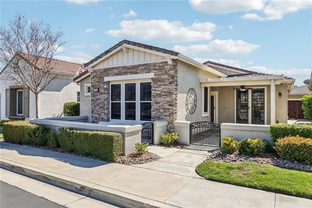 view of front of property featuring a fenced front yard, stone siding, stucco siding, and a gate