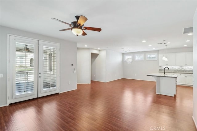 unfurnished living room with a sink, a healthy amount of sunlight, dark wood-style floors, and a ceiling fan