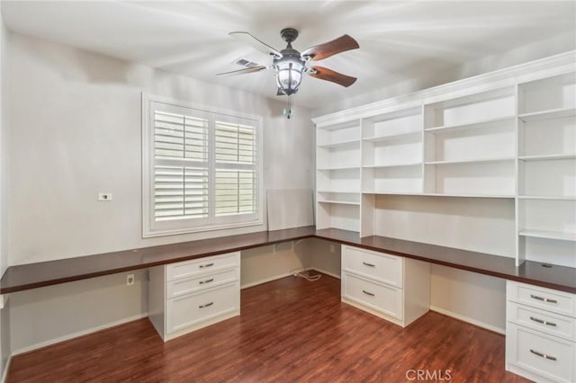 unfurnished office with visible vents, built in study area, ceiling fan, and dark wood-style flooring