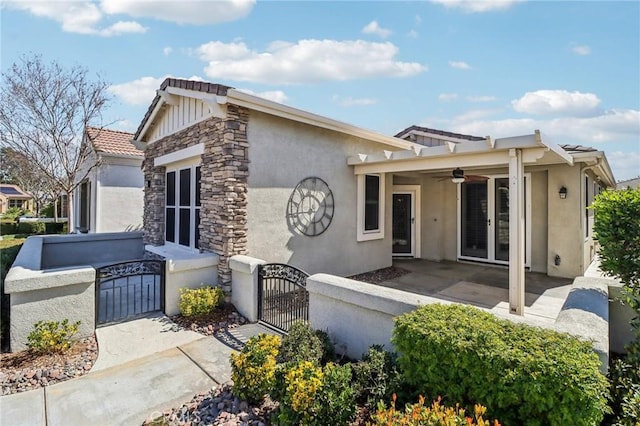 view of front of house featuring a patio, a gate, a ceiling fan, french doors, and stone siding