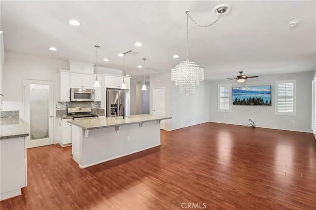 kitchen with stainless steel appliances, wood finished floors, an island with sink, and white cabinets