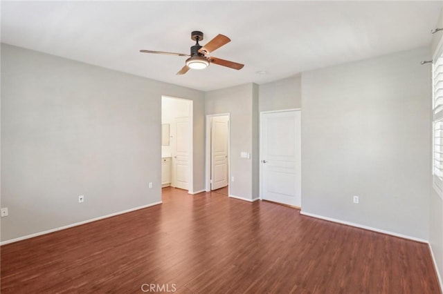 unfurnished bedroom featuring a ceiling fan, ensuite bath, baseboards, and dark wood-style flooring