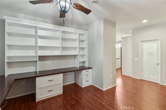 unfurnished office with baseboards, dark wood finished floors, built in desk, recessed lighting, and a ceiling fan