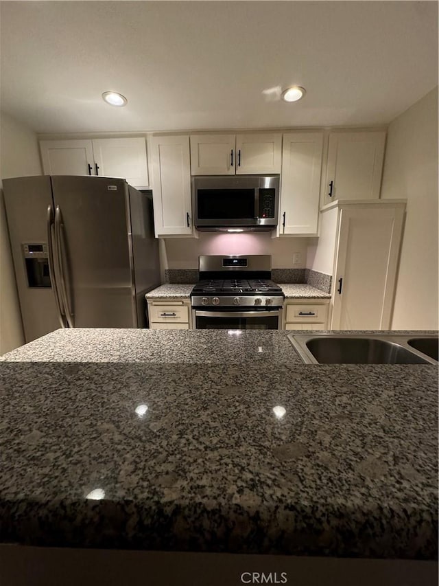 kitchen with white cabinetry, dark stone counters, recessed lighting, and stainless steel appliances