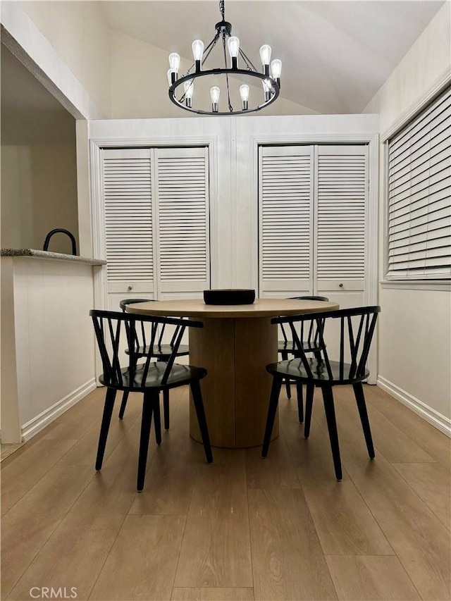 unfurnished dining area featuring an inviting chandelier, lofted ceiling, wood finished floors, and baseboards