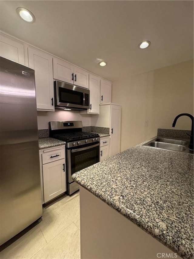 kitchen featuring a sink, dark stone countertops, white cabinetry, recessed lighting, and stainless steel appliances