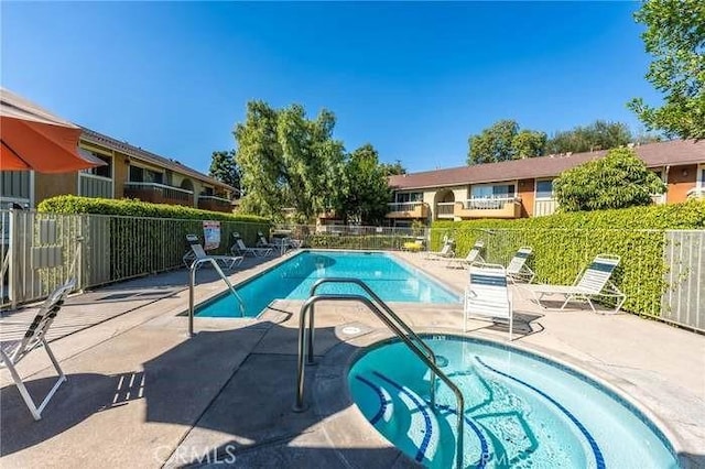 community pool featuring a patio, fence, and a hot tub