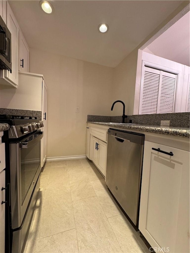 kitchen with baseboards, recessed lighting, a sink, stainless steel appliances, and white cabinetry