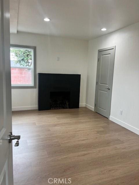 unfurnished living room with a fireplace, recessed lighting, wood finished floors, and baseboards