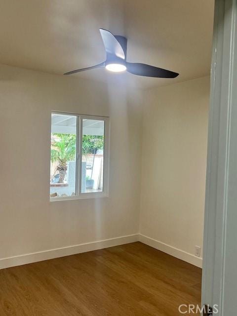 spare room with a ceiling fan, dark wood-style floors, and baseboards