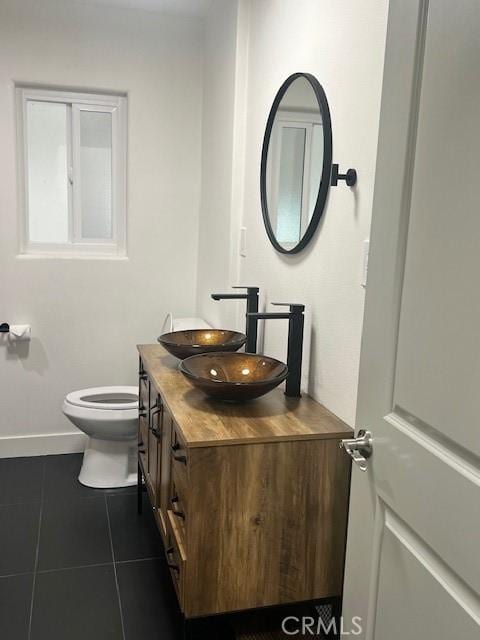 half bath featuring tile patterned flooring, toilet, vanity, and baseboards