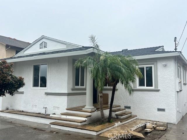 view of front of home with crawl space, stucco siding, and roof with shingles