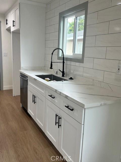 kitchen featuring wood finished floors, a sink, white cabinets, dishwasher, and backsplash